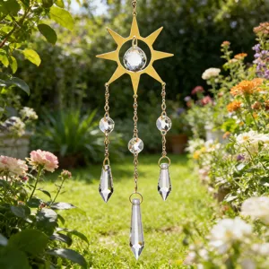 Acchiappasole a sole in metallo dorato con prismi di cristallo in un giardino fiorito.