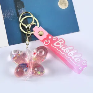 Detailansicht des rosa Schmetterlings-Schlüsselanhängers mit Pailletten und Flüssigkeit.