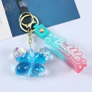 Nahaufnahme eines blauen Schmetterlings-Schlüsselanhängers mit flüssigem Glitzer und Silikonband