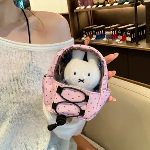 Detail of a pink polka dot mini backpack doll pouch keychain with a plush rabbit inside