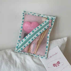 Detail van roze mesh opbergtas met blauwe stippenrand en diagonale ritssluiting.