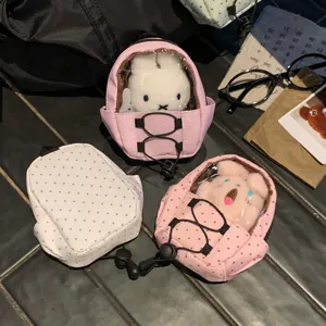 Detail showing a mini pink polka dot backpack doll carrier with a plush rabbit inside.