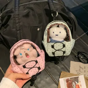 Detail of polka dot mini backpack doll carrier keychain attached to a black bag