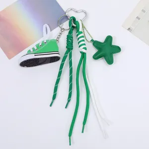 Close-up detail of a green canvas shoe keychain with woven rope tassels and a star charm