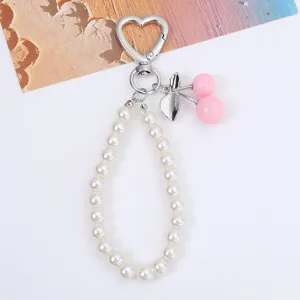 Detail view of sweet cherry and pearl keychain with heart-shaped silver clasp
