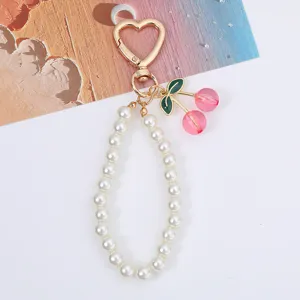 Close-up view of a sweet pearl phone strap featuring pink cherry charms and a gold heart clasp.