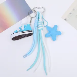 Detail view of a keychain with blue canvas shoe and star charms on braided ropes