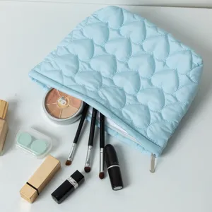 Light blue quilted heart pattern cosmetic bag filled with makeup brushes and lipsticks.