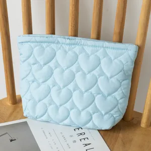Detail view of a light blue heart-shaped quilted pouch on a natural wooden chair