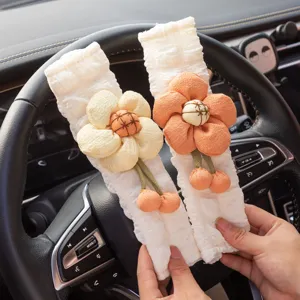 Nahaufnahme von weißen Autogurt-Schonern mit niedlichen Plüschblumen-Verzierungen.