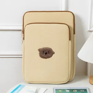 Detail of cute embroidered otter iPad sleeve and laptop case on a minimalist desk setup