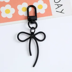 Macro detail of a minimalist black alloy bow keychain with a matching lobster clasp