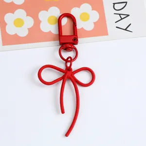 Close-up view of a vibrant matte red metal bow keychain charm for DIY bag accessories
