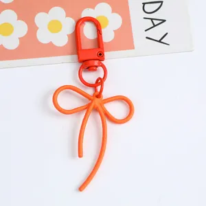 Close-up detail of the vibrant orange alloy bow keychain with a secure lobster clasp hook