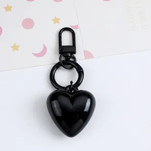 Close-up detail of a glossy black resin heart keychain with matching black metal hardware
