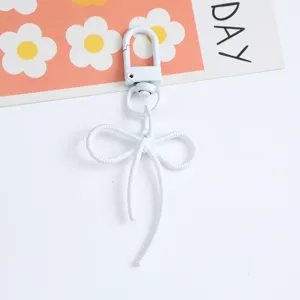Detailed view of a white alloy bow-shaped keychain with a sturdy spring clasp.