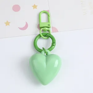 Macro view of a mint green candy-colored resin heart keychain with matching carabiner hooks