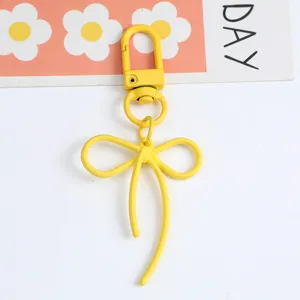Detailed view of a yellow matte alloy bow-shaped keychain with a secure lobster clasp