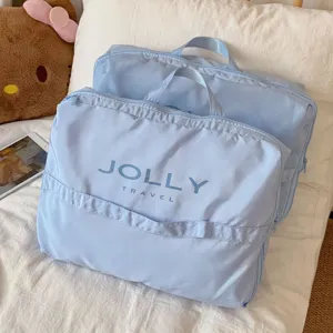 Vista detallada de bolsas de viaje azul claro con estampado JOLLY TRAVEL en cama