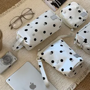 Close-up of white polka dot pencil cases with silver butterfly accents and pearl zippers.