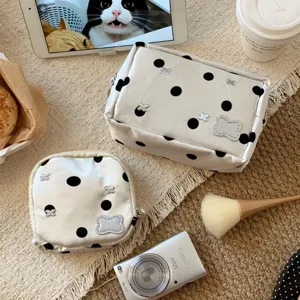 Detailed view of white polka dot cosmetic pouches with silver bow charms on a rug