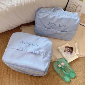 Set de organizadores de viaje azul claro con logo JOLLY TRAVEL en un fondo de cama acogedor