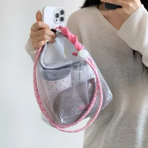 Detail view of a white mesh beach bag with pink rope handle showing its storage capacity.