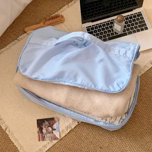 Detalle de un organizador de viaje azul claro con jerséis y ropa doblada en su interior