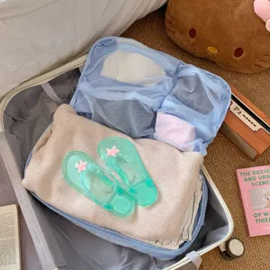 Bolsas organizadoras de viaje de malla azul empacadas en una maleta con ropa doblada