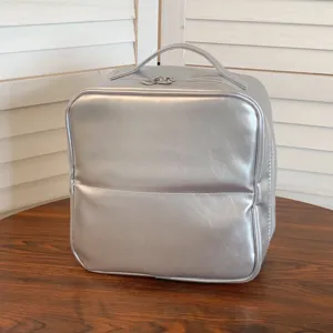 Close-up detail view of a stylish silver PU leather makeup storage bag on a wooden surface