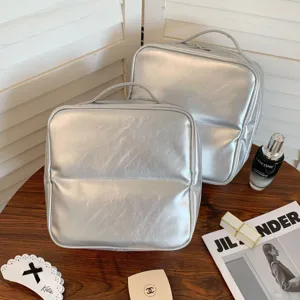 Silver PU leather cosmetic travel storage bags with metallic finish on wooden table