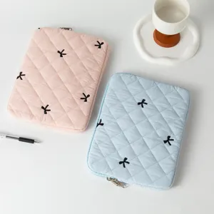 Close-up of pink and blue quilted laptop sleeves with cute embroidered bow details