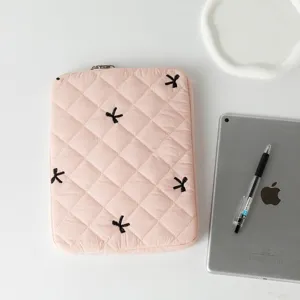 Close-up of pink quilted tablet sleeve featuring black embroidered bow accents for laptop