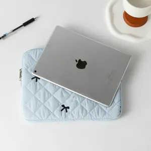 Blue quilted tablet sleeve with embroidered bows shown with a silver iPad for scale.