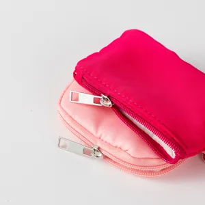 Primer plano de mini carteras de nailon para monedas con cremalleras en rosa y magenta.
