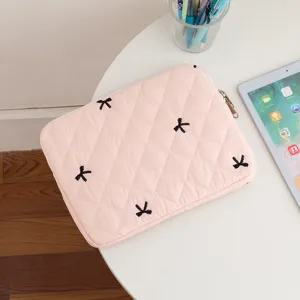 Close-up of pink quilted tablet sleeve featuring black embroidered bow details