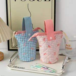 Vue détaillée des trousses à crayons matelassées à nœuds en bleu et rose sur plateau