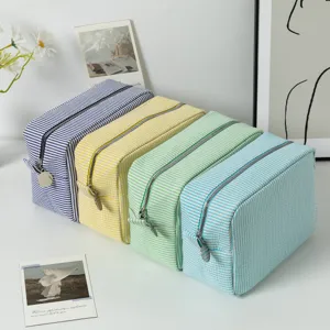 Detailed view of four colorful striped seersucker makeup bags for travel organization