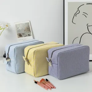 Macro view of three striped seersucker cosmetic bags in blue, yellow and navy.