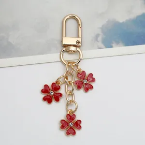 Close-up of red flower pendants on a gold alloy keychain with sparkly crystal centers.