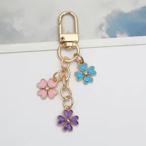 Close-up detail of a gold alloy keychain with three colorful enamel flower charms