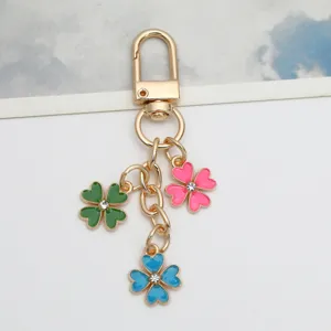 Gold alloy keychain with three colorful enamel four-leaf clover charms and rhinestones.