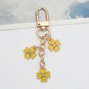 Macro detail of a yellow floral four-leaf clover keychain with golden lobster clasp