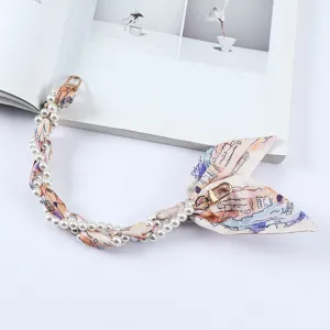 Detailweergave van het elegante parel- en zijden sjaaltelefoonkoord met gouden clips