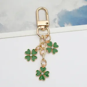 Close-up of a gold-tone keychain featuring three green shamrock charms with crystal centers.