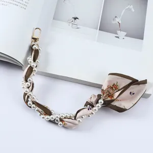 Detailopname van bloemen zijden sjaal en parelmoer telefoonkoord met gouden metalen clips