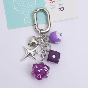 Detailed macro view showing purple dice and billiard ball charms on a silver carabiner keychain