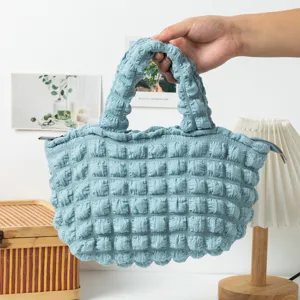 Primer plano de un bolso azul con textura de burbujas sostenido en un interior acogedor