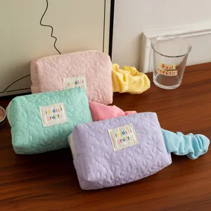 Detailed view of candy-colored quilted floral cosmetic storage bags on a wooden desk