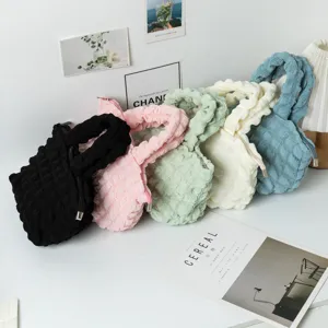 Primer plano de bolsos plisados de burbujas en colores rosa, azul, verde y crema.